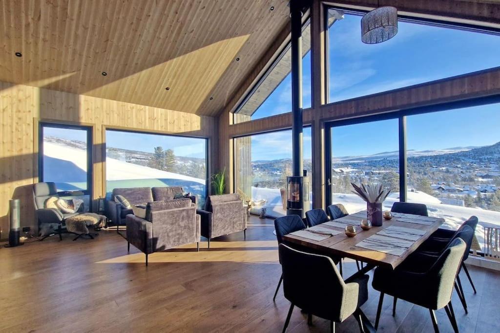 a dining room with a table and chairs and windows at Panorama Hovden - New Cabin With Amazing Views in Hovden