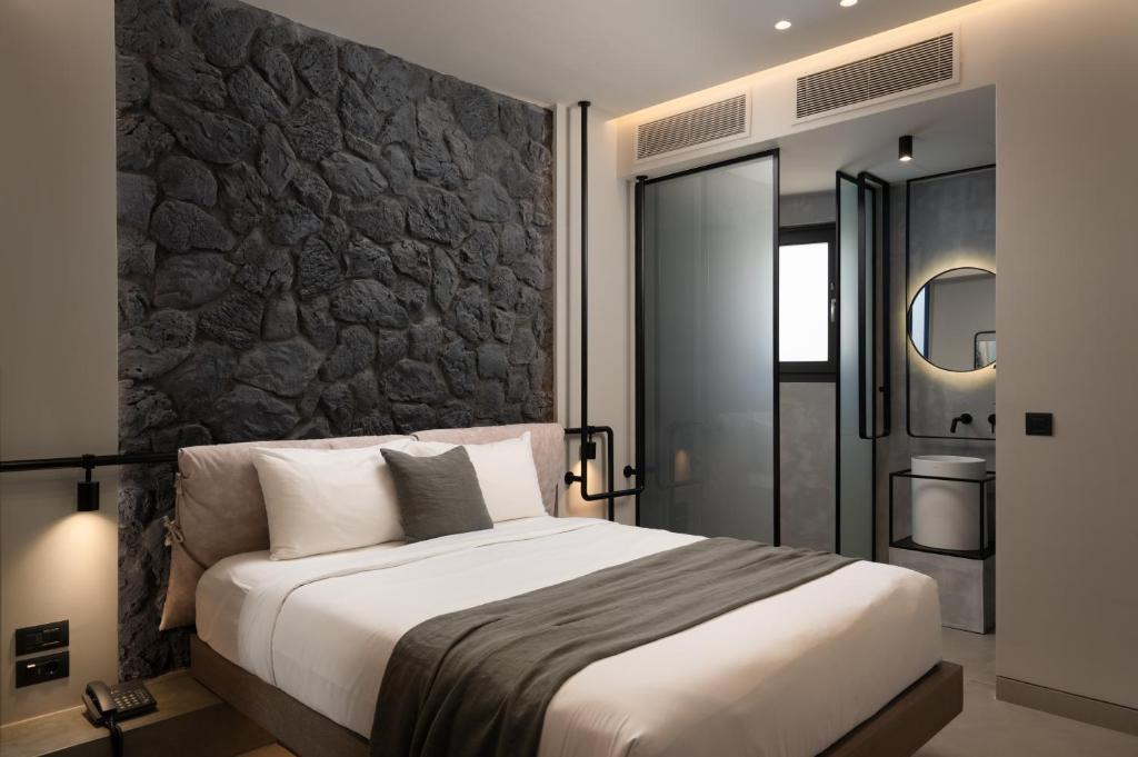 a bedroom with a large bed and a stone wall at Apikia Santorini in Pirgos