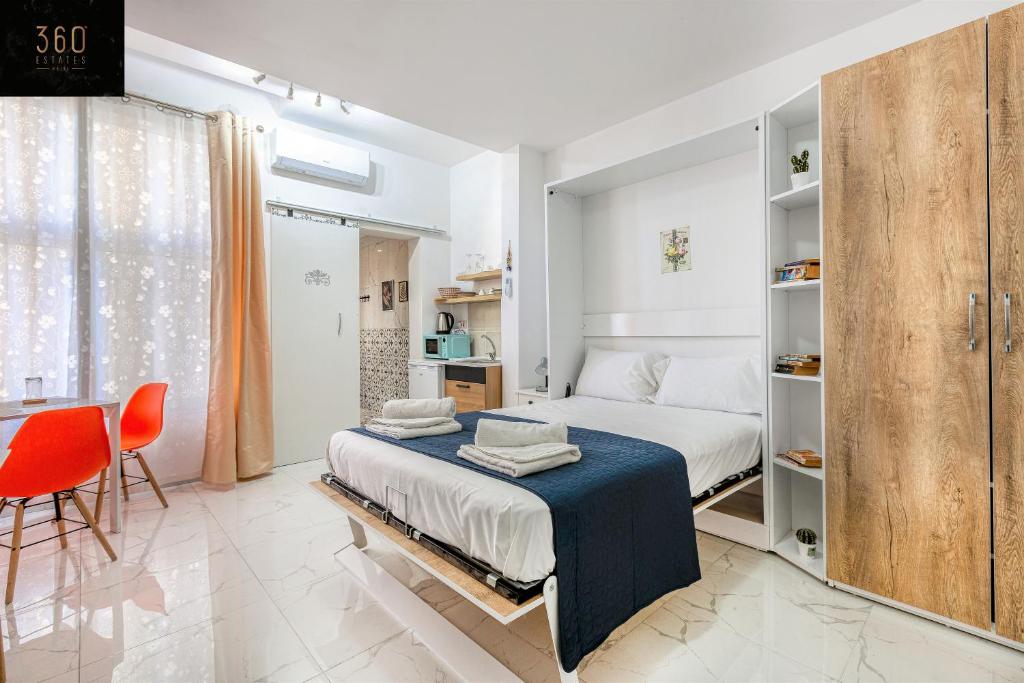 um quarto branco com uma cama e uma cadeira vermelha em The Sliema Studio Stay by 360 Estates em Sliema
