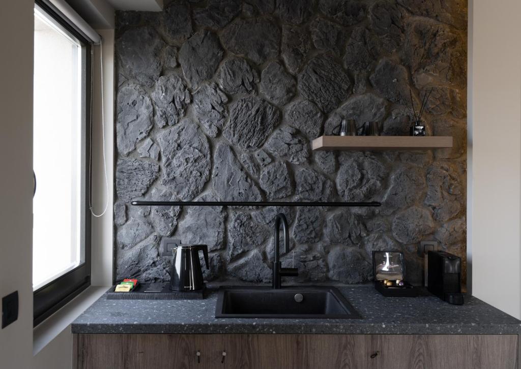 a kitchen with a sink and a stone wall at Apikia Santorini in Pirgos