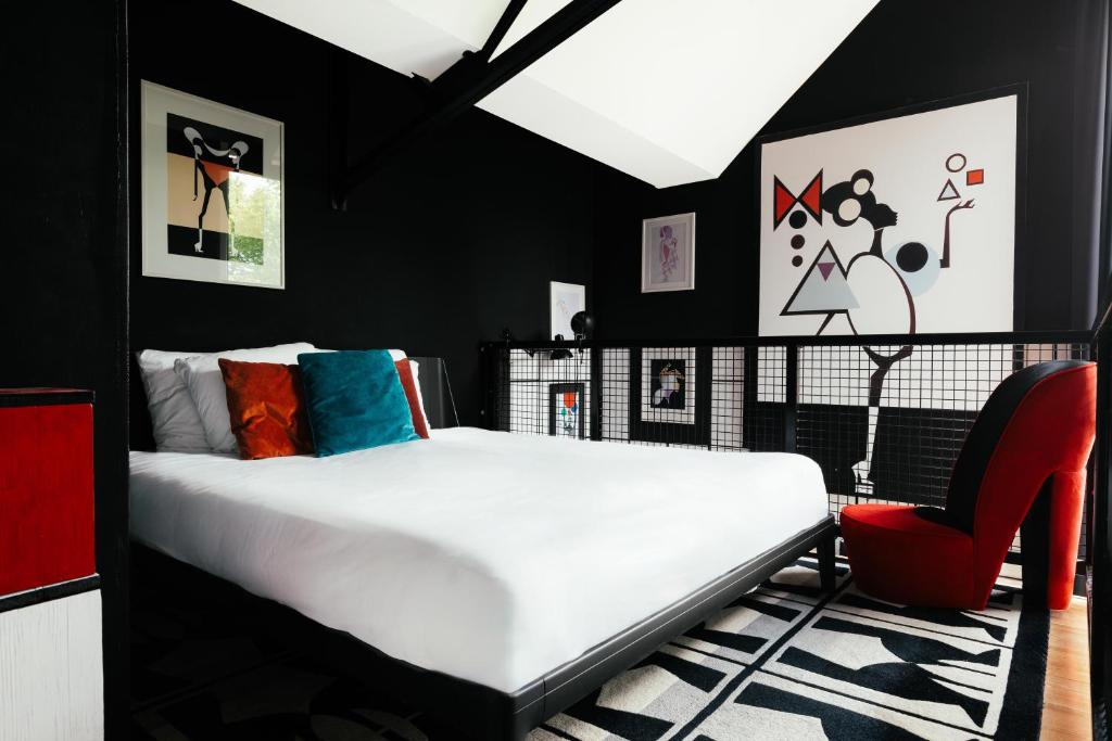 a bedroom with a white bed and a red chair at Design Hotel Modez in Arnhem