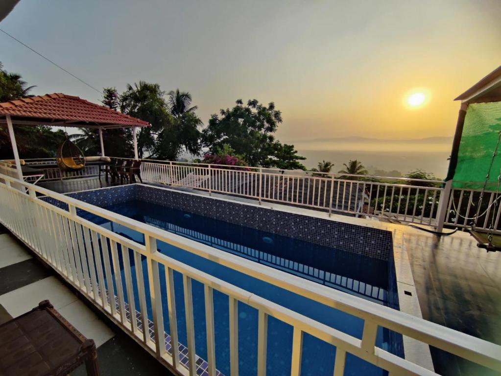 a swimming pool on a balcony with the sunset at WhiteHouse Home stay by Oxystays in Alibaug