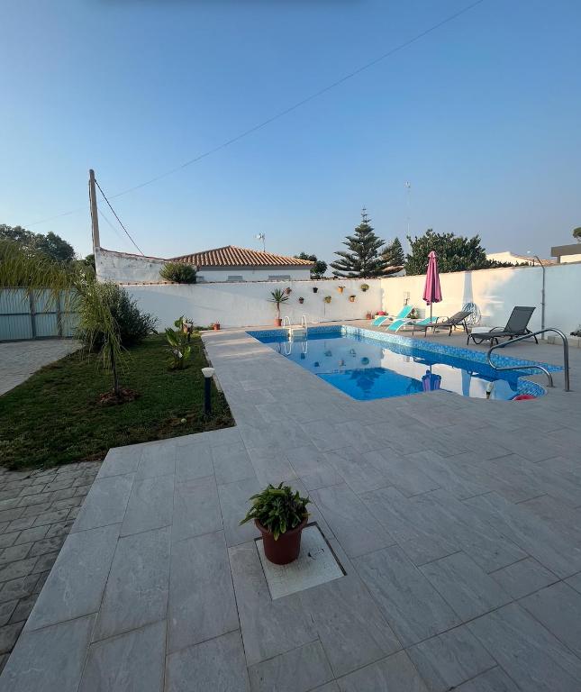 a swimming pool in a yard with a patio at Fantástico chalet con piscina 2 km de la barrosa in Chiclana de la Frontera