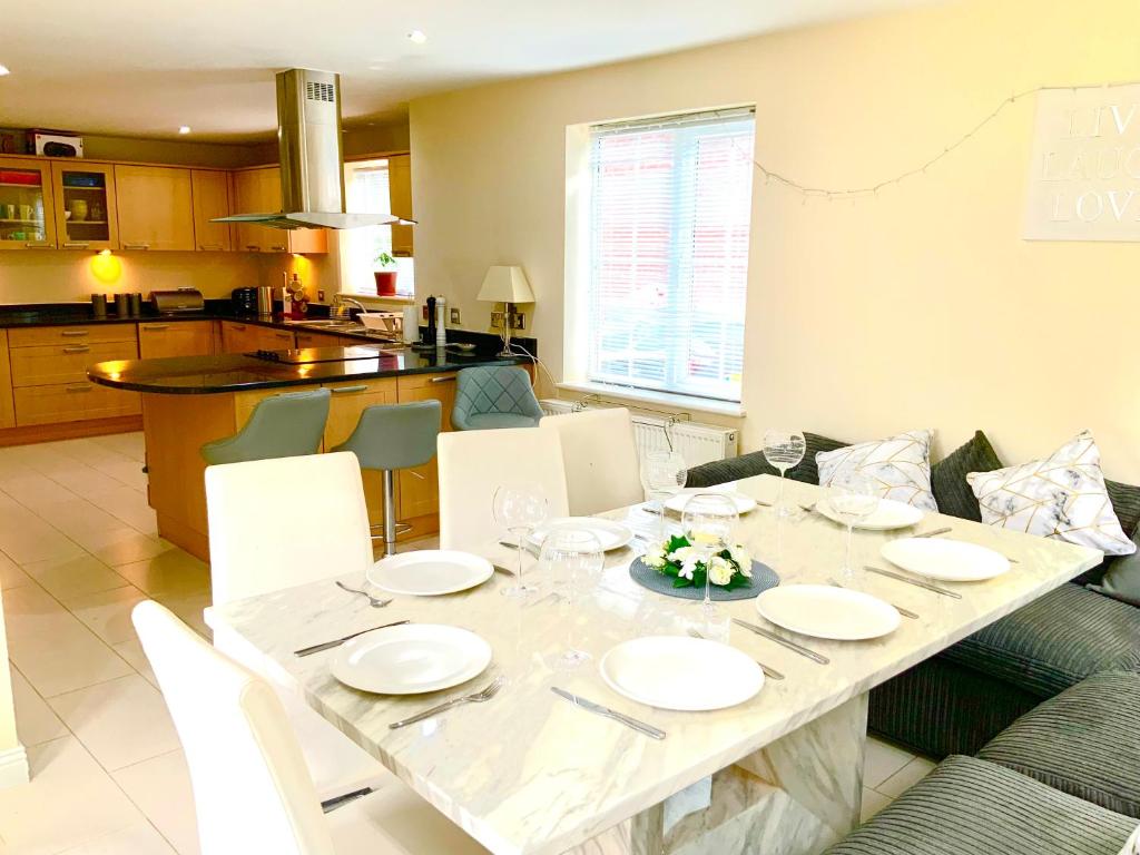 - une table à manger avec des plaques blanches dans l'établissement Large Executive 4-Bed Detached House in Miskin, Cardiff-sleeps up to 10, à Hensol