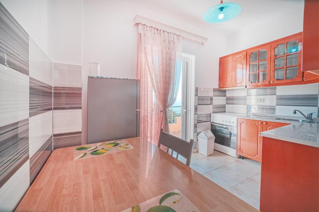 a kitchen with orange cabinets and a table with a chair at Mirror Beach Ksamil - Vila Zervo in Sarandë