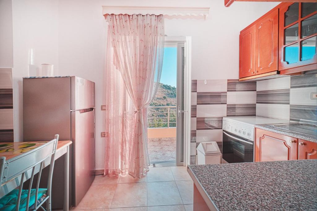 a kitchen with a refrigerator and a sliding glass door at Mirror Beach Ksamil - Vila Zervo in Sarandë
