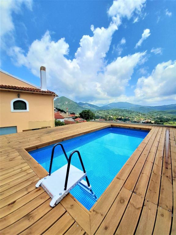 a swimming pool on a wooden deck with a chair next to it at VILLA CHRYSANTHOS in Ágios Matthaíos