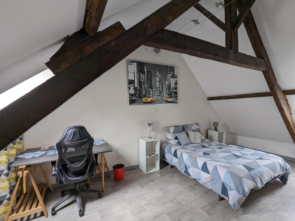 een slaapkamer met een bed en een bureau op zolder bij Appart à coté de la vieille ville de Boulogne sur mer in Boulogne-sur-Mer