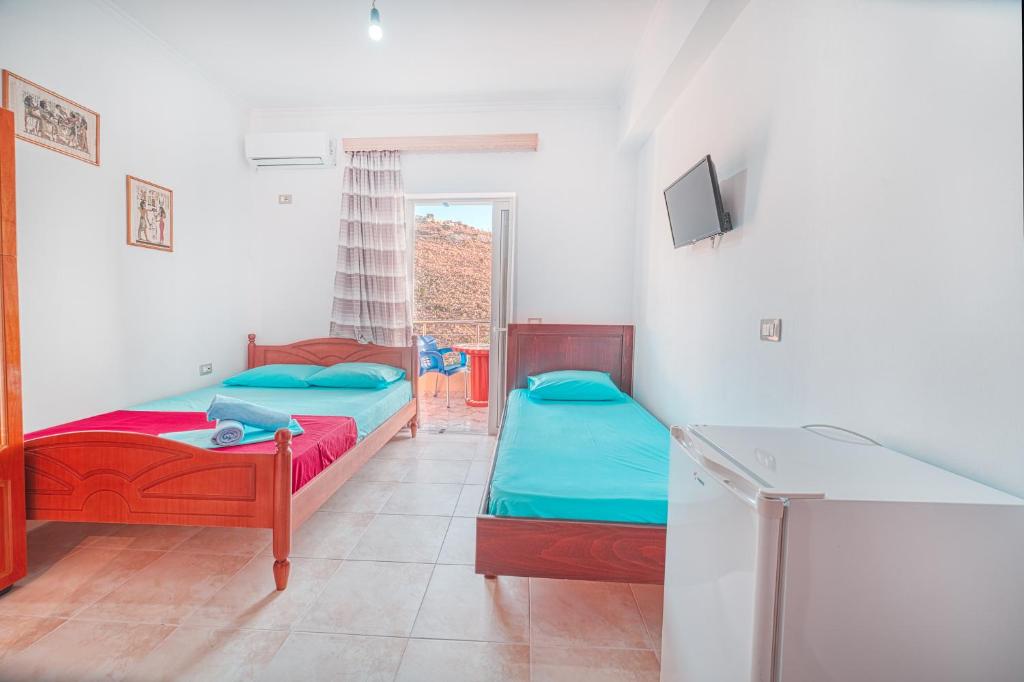 a room with two beds and a tv in it at Mirror Beach Ksamil - Vila Zervo in Sarandë