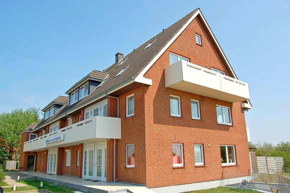 a large red brick building with a balcony at Haus am Golfplatz Nr 06 Ferienwohnung Strandblick in Süderhöft