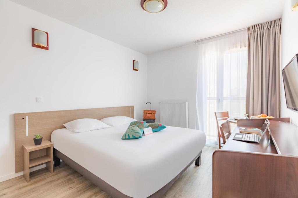 a hotel room with a large white bed and a desk at Appart'City Classic Chalon sur Saone in Chalon-sur-Saône