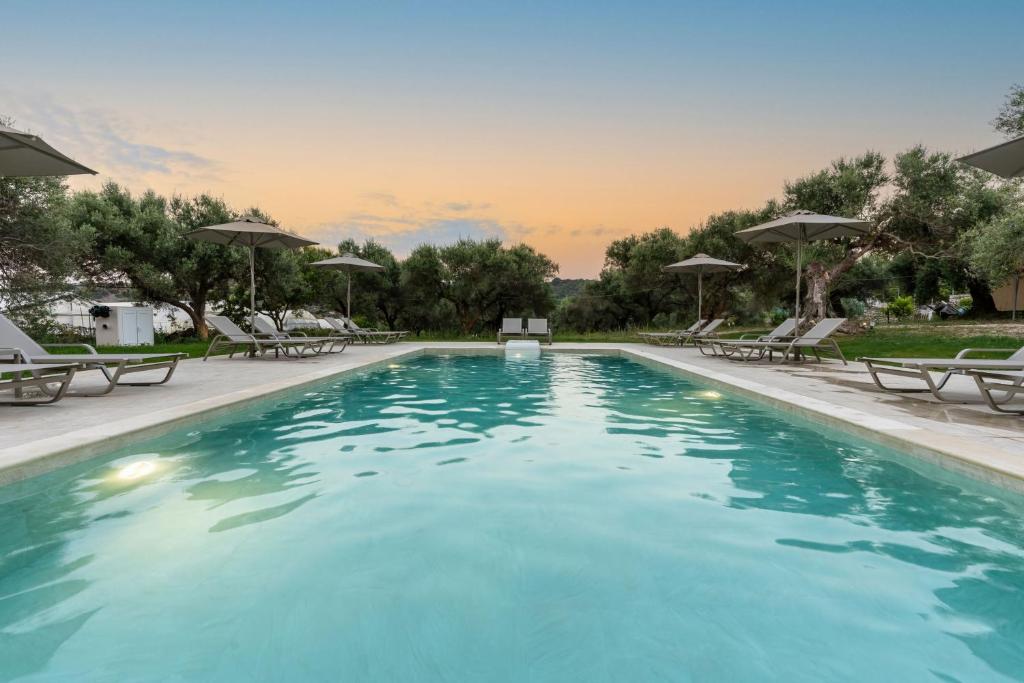 a large swimming pool with chairs and umbrellas at Lyrids Apartments in Episkopí- Rethimno