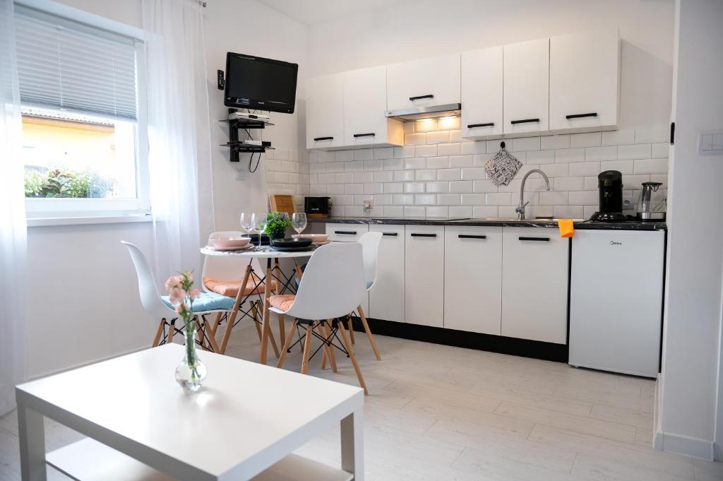 una cocina con armarios blancos y una mesa con sillas. en Emma Apartamenty, en Gostyń