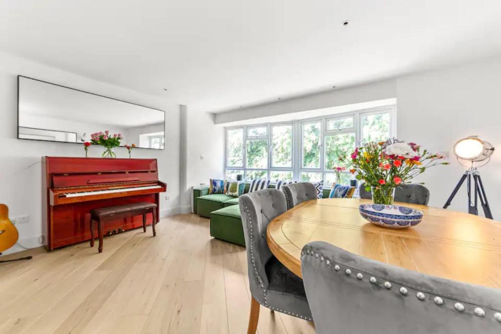 a living room with a table and a piano at Serene 3BD Flat view of the Thames - Hammersmith in London