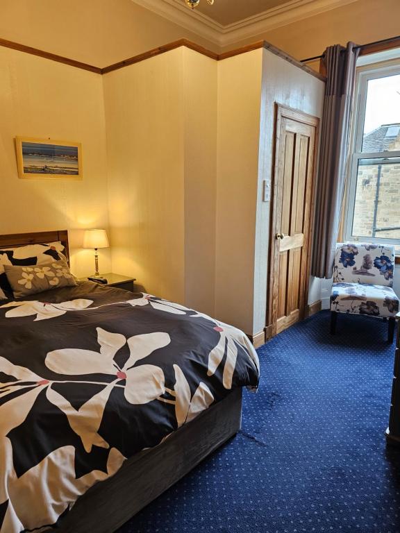 um quarto com uma cama, uma cadeira e uma janela em Smiths Guest House em Edinburgo