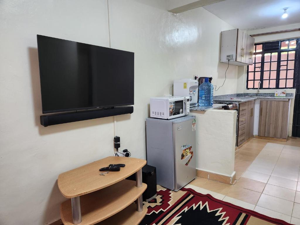 a kitchen with a table and a television on the wall at Zuri Homes 2 in Keruguya