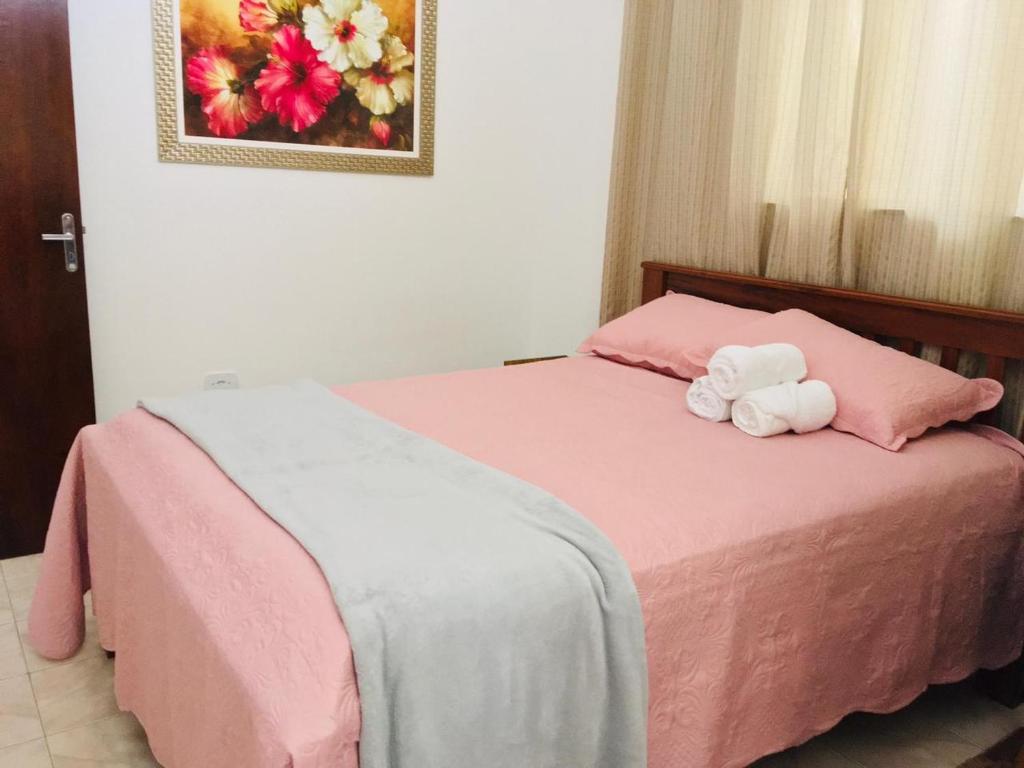 a pink bed with a stuffed animal sitting on it at Hospedagem Alto da Montanha in Cunha