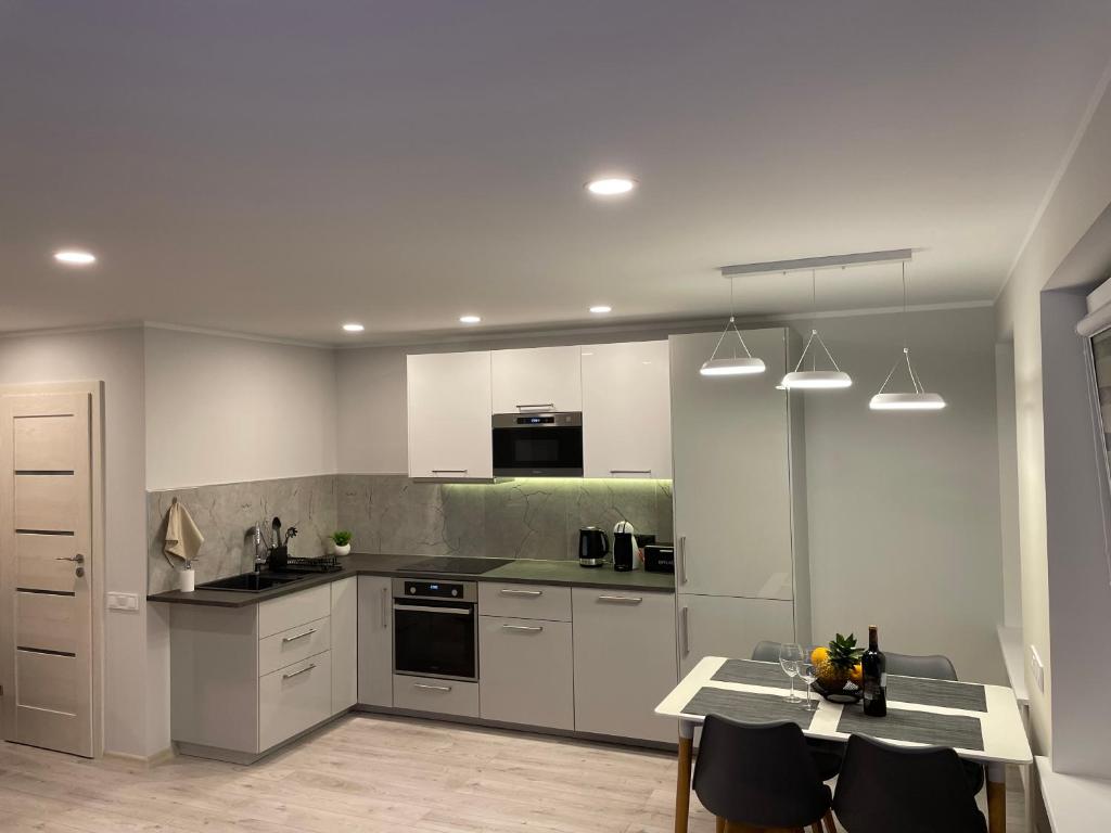 a kitchen with white cabinets and a table with chairs at Family Getaway By The Sea in Jūrmala