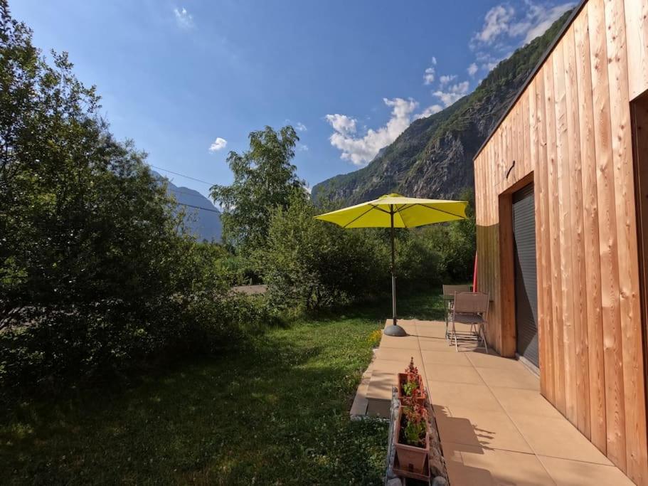 a yellow umbrella sitting on a patio next to a building at Oisans Chalet indépendant in Le Vert