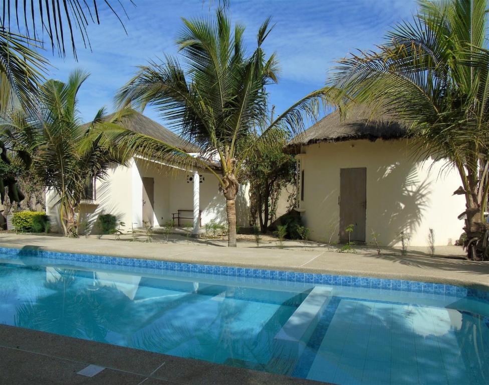 ein Haus mit einem Pool und Palmen in der Unterkunft WouroBa in Mbodiène