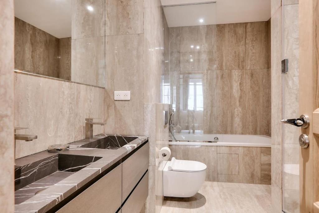 a bathroom with a toilet and a sink and a tub at Le luxe à la Française au cœur de Paris in Paris
