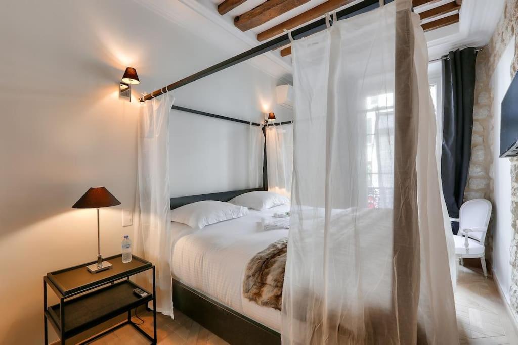 a bedroom with a canopy bed with a window at Le luxe à la Française au cœur de Paris in Paris