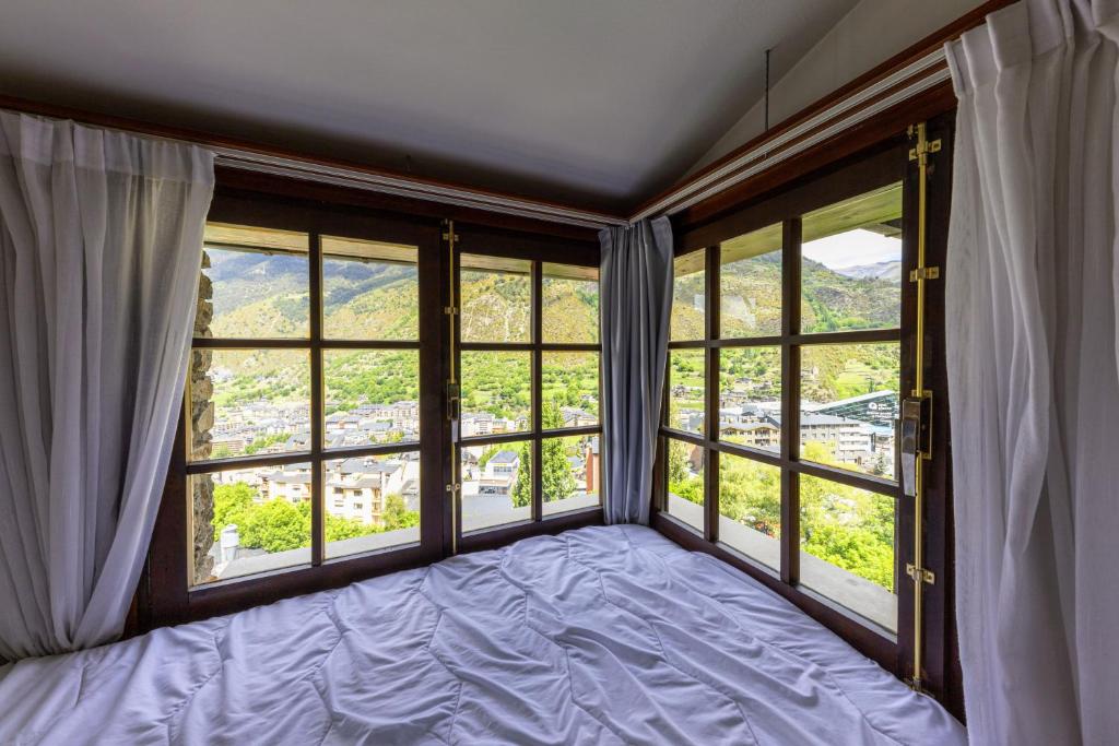 um quarto com janelas grandes e uma cama na frente em La Solana Apartaments & Spa em Encamp