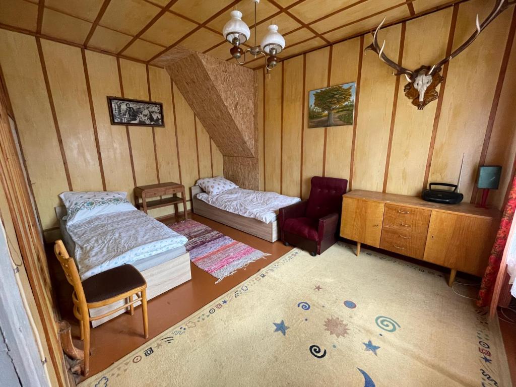 sypialnia z 2 łóżkami i krzesłem w pokoju w obiekcie Pod Dębem w Białowieży
