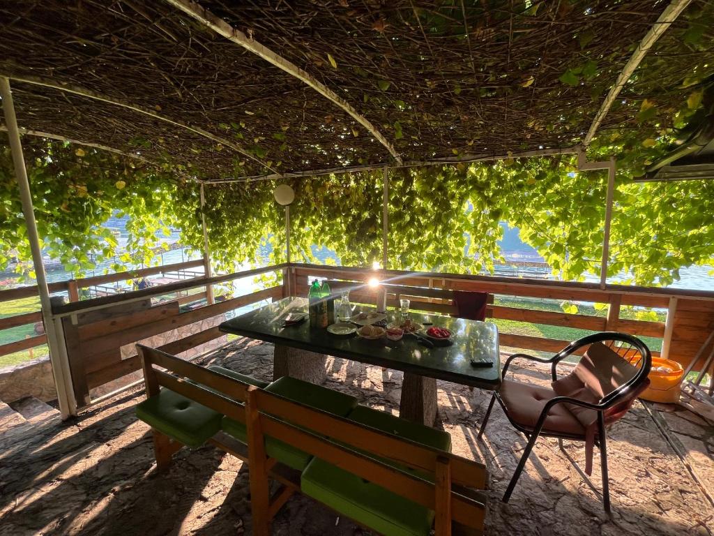 a table and chairs on a porch with vines at Rustic Heaven Ostrožac Cottage houses in Jablanica