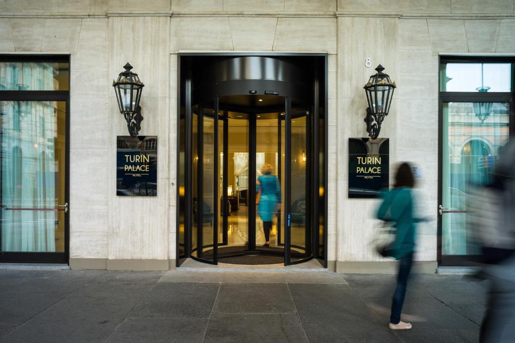a woman walking into a building with a revolving door at Turin Palace Hotel in Turin