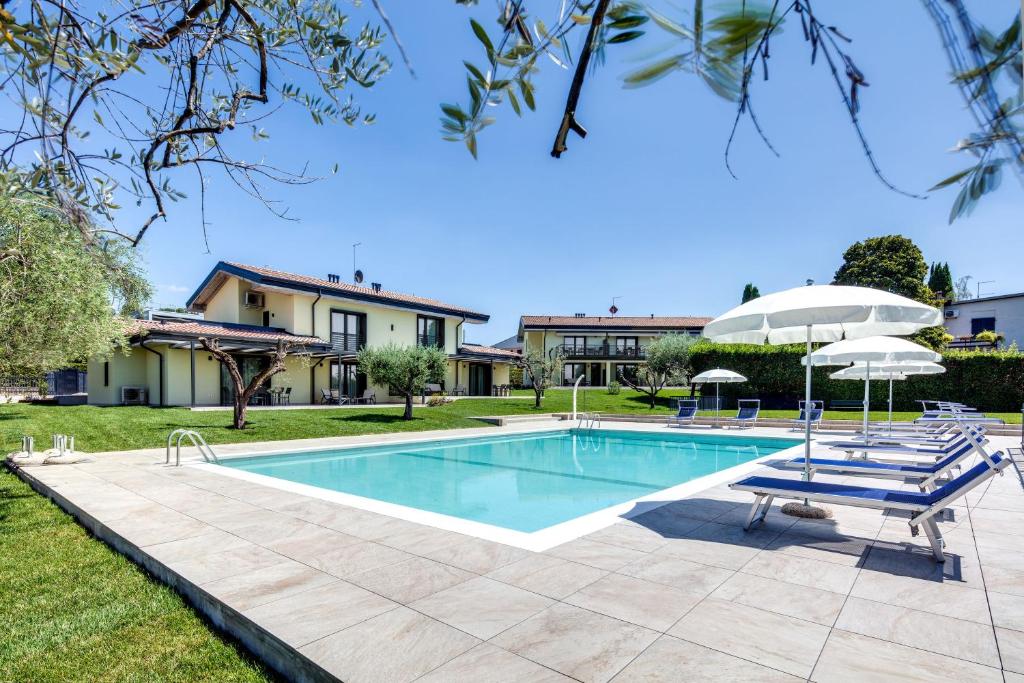 a swimming pool with chairs and umbrellas in a yard at Oleandro Holiday Apartments in Bardolino