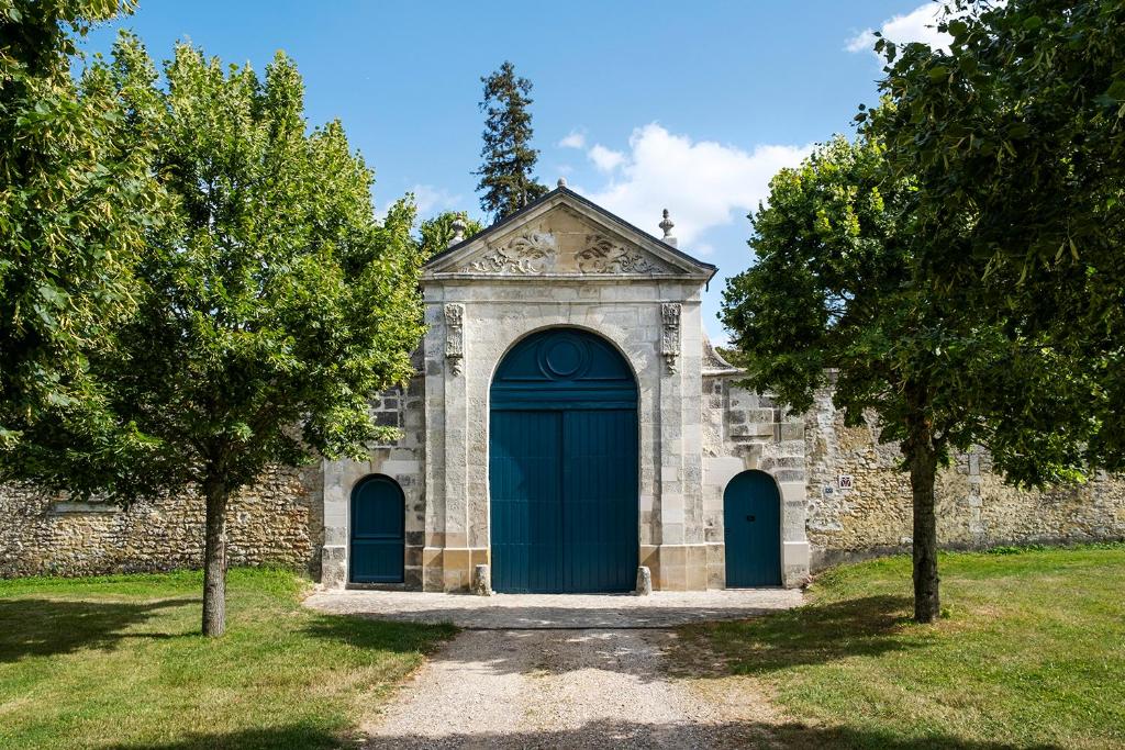 een oude kerk met een blauwe deur en twee bomen bij Abbaye du Trésor in Bus-Saint-Rémy