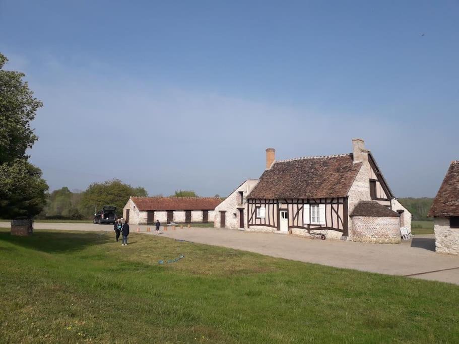 a group of buildings with people walking in front of them at Les Hautes Charmante Ferme solognote in Ligny-le-Ribault