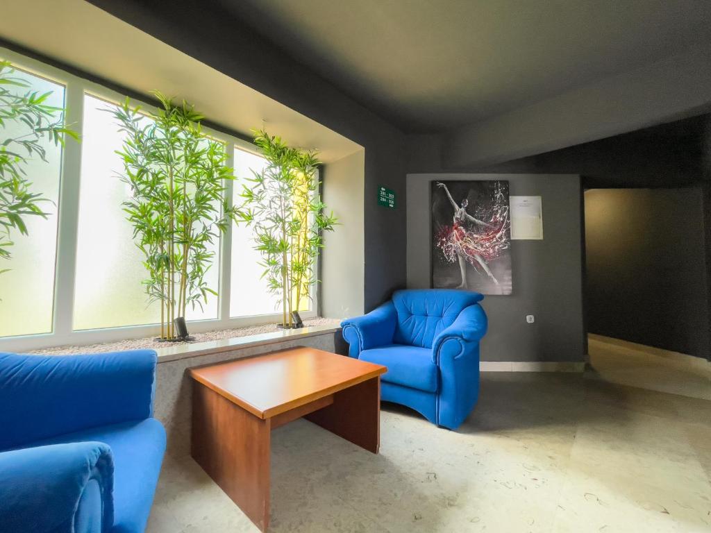 een woonkamer met blauwe stoelen, een tafel en ramen bij GRAND - Premium rooms & apartments in Selce