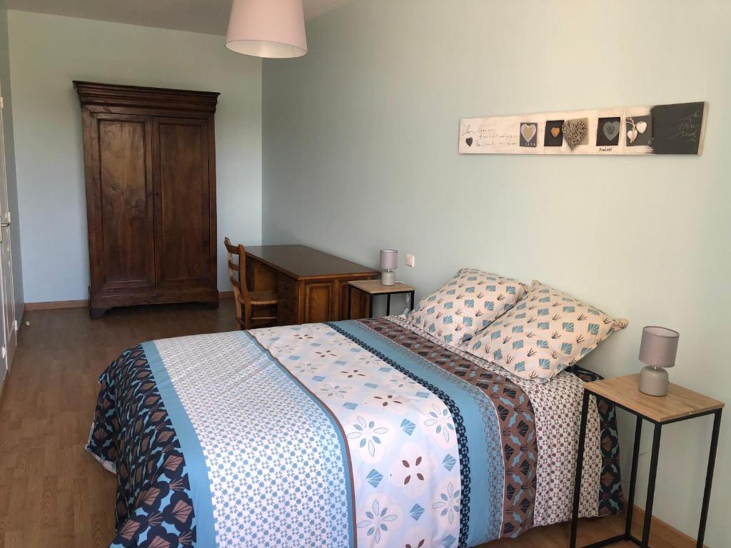Schlafzimmer mit einem Bett, einem Schreibtisch und einem Tisch in der Unterkunft Au pied du Marché in La Châtre
