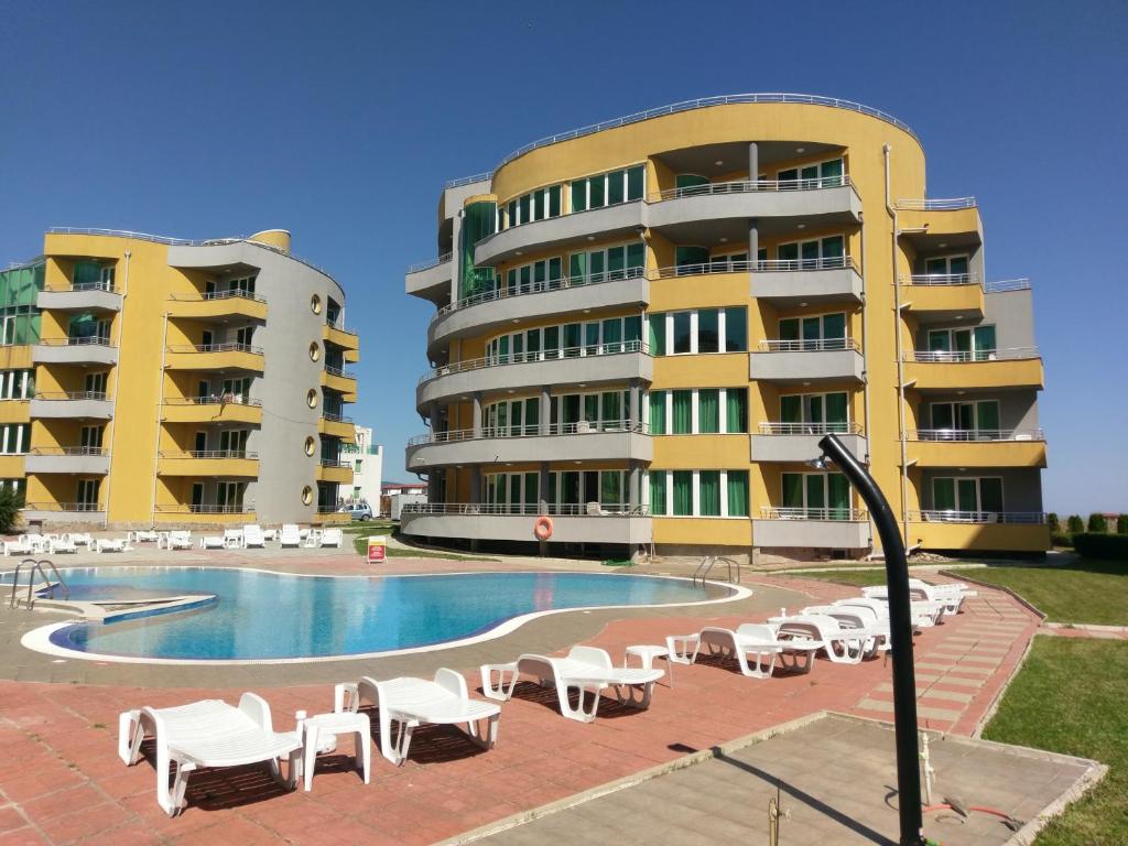 a large building with a swimming pool and white chairs at Sinemorets Cliffs in Sinemorets