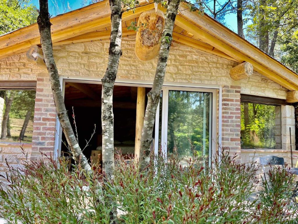 une petite maison en briques avec des fenêtres et des arbres dans l'établissement Le doux refuge, à Gagnières