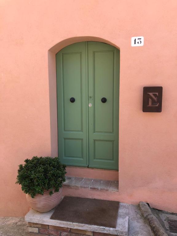 een groene deur op een roze gebouw met een potplant bij TRUFFLE'N'BED in San Giovanni dʼAsso