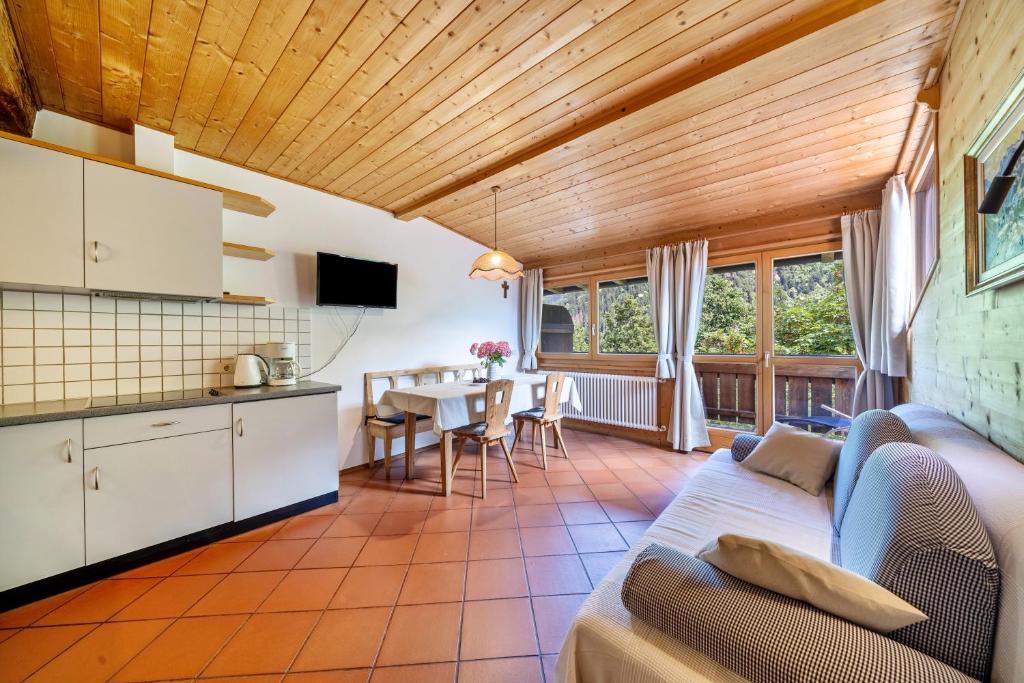 Il dispose d'une cuisine et d'un salon avec un canapé et une table. dans l'établissement Mayrhof Apartment Ahorn, à San Pancrazio