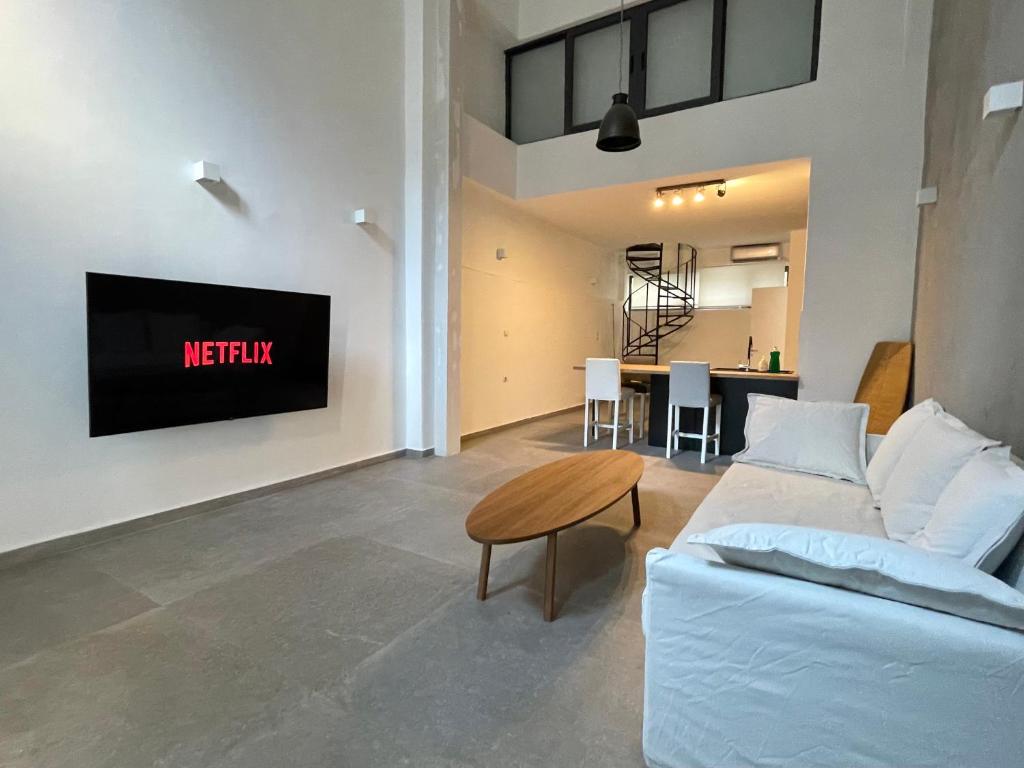 a living room with a couch and a tv on a wall at Loft studio in Pagrati in Athens