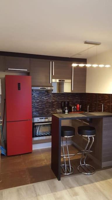 Il comprend une cuisine équipée d'un réfrigérateur rouge et d'un comptoir avec tabourets. dans l'établissement Appartement très calme, proche du stade de la Beaujoire, à Nantes