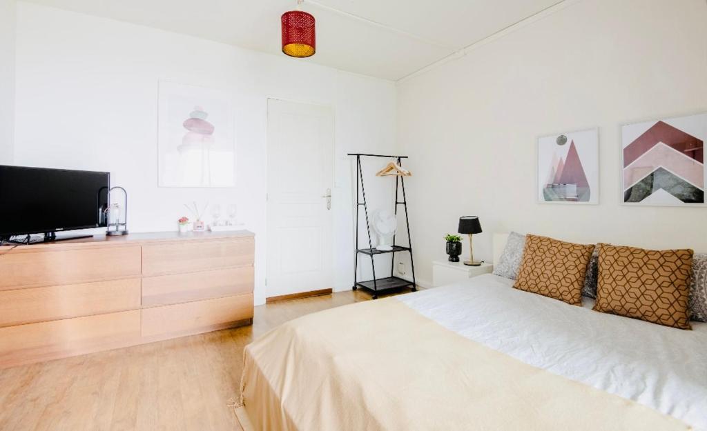 a bedroom with a bed and a flat screen tv at Chambre privée avec petit salon extérieur in Bordeaux