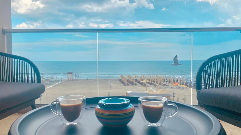 a table with two glasses and a view of the beach at La malul marii in Mamaia Nord
