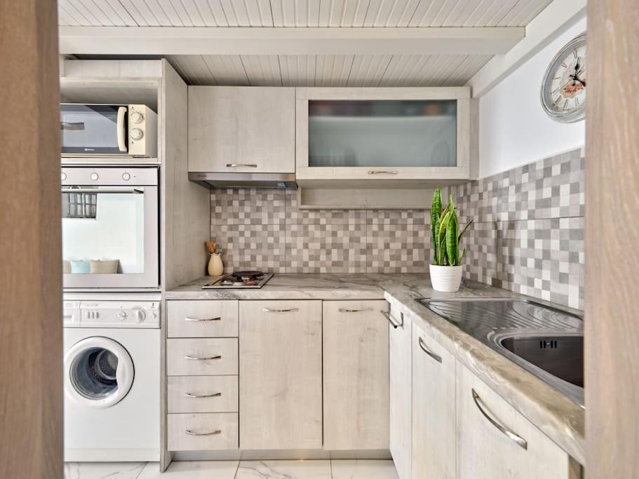 a white kitchen with a sink and a dishwasher at Lindo House in Lefkes