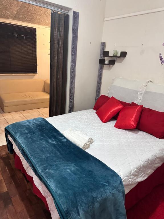 a bedroom with a bed with red pillows on it at Nomacurvy guest house in Roodepoort