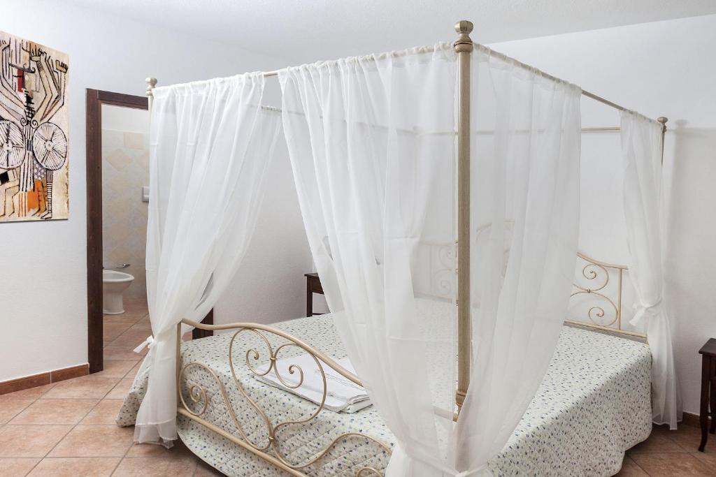 een slaapkamer met een hemelbed en witte gordijnen bij Managheri Wine Bar in Oliena