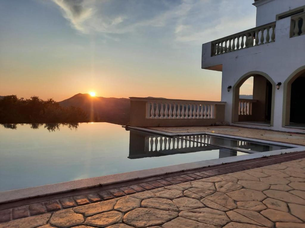 a house with a pool in front of a sunset at Olive Villa in Episkopianá