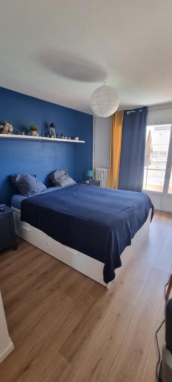 ein blaues Schlafzimmer mit einem großen Bett und einer blauen Wand in der Unterkunft Grand appart plein sud in La Seyne-sur-Mer