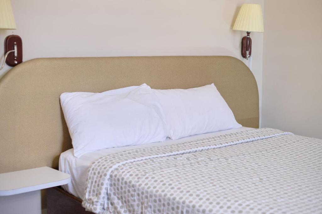 una cama con almohadas blancas encima en Gess Hotel en Paramaribo