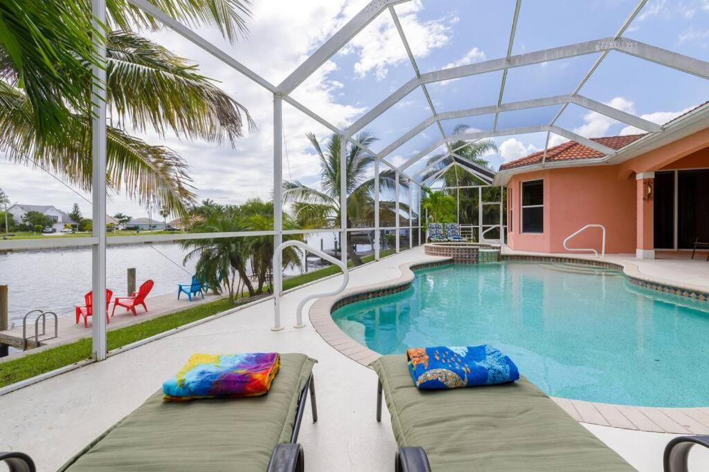 een zwembad met 2 ligstoelen voor een huis bij Villa Maxos - Boaters dream 4br/3 bath pool / spa in Cape Coral
